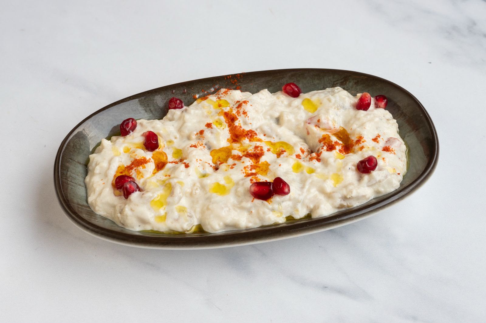 Creamy baba ghanoush smoked aubergine dip finished with paprika, olive oil and pomegranate seeds.