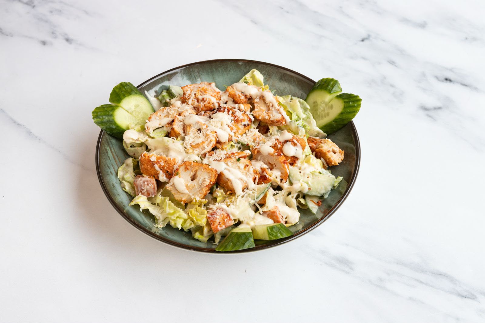 Chicken caesar salad with crispy chicken, parmesan and cucumber.