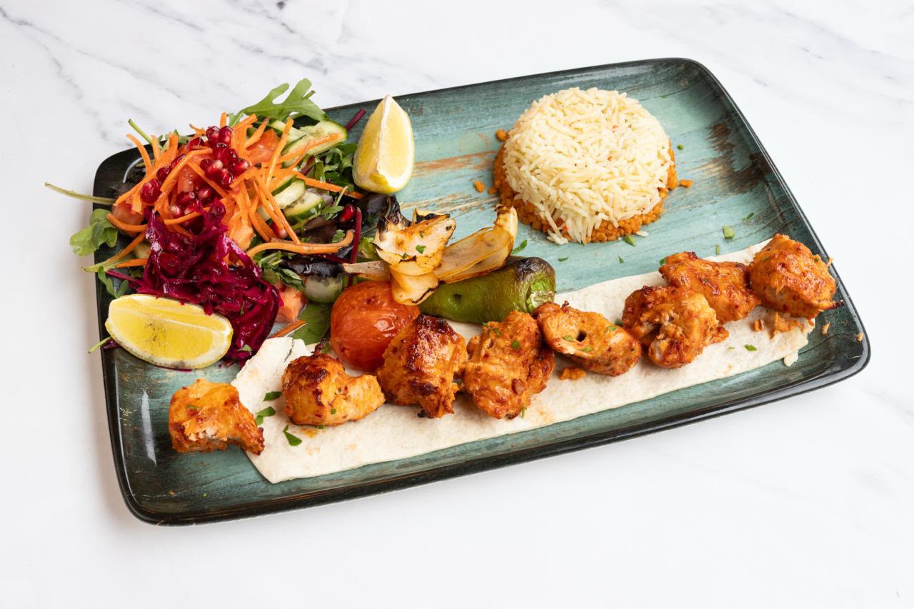 Char-grilled chicken shish kebab on flatbread with rice, grilled vegetables and house salad.