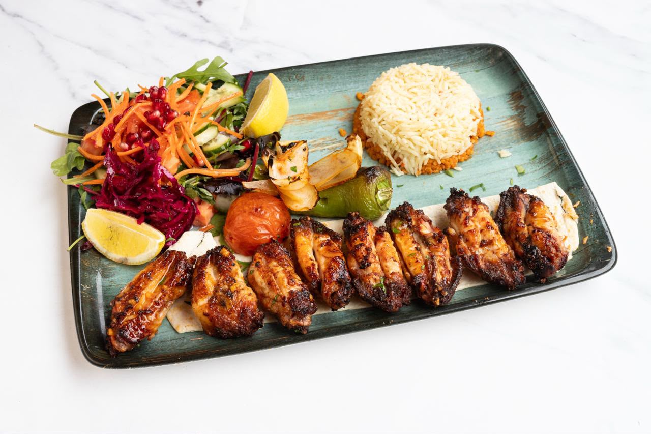 Char-grilled marinated chicken wings with rice, salad and grilled vegetables.
