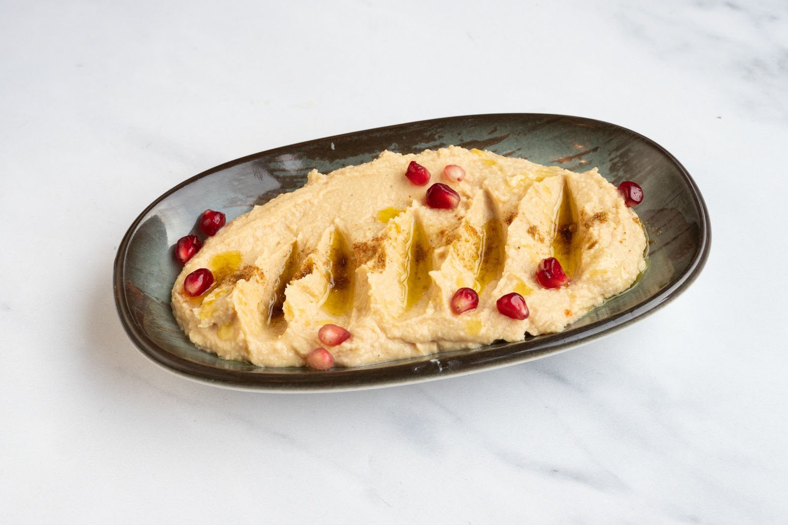 Silky hummus swirled with olive oil, cumin and pomegranate seeds, a meze staple at The Kervan.