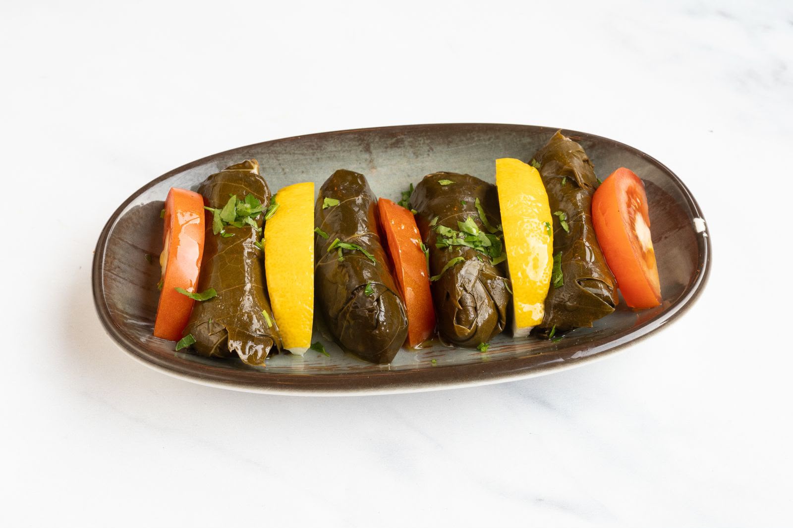 Stuffed vine leaves (dolma) with lemon, tomato and fresh parsley.