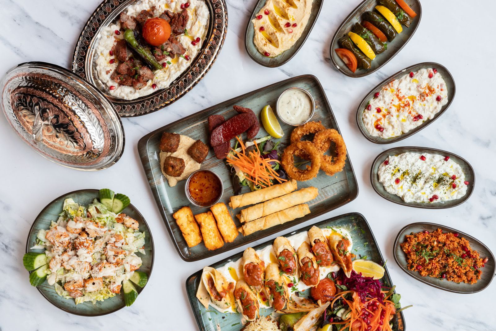 Overhead spread of Kervan platters including meze dips, hot starters, beyti wraps and salads.