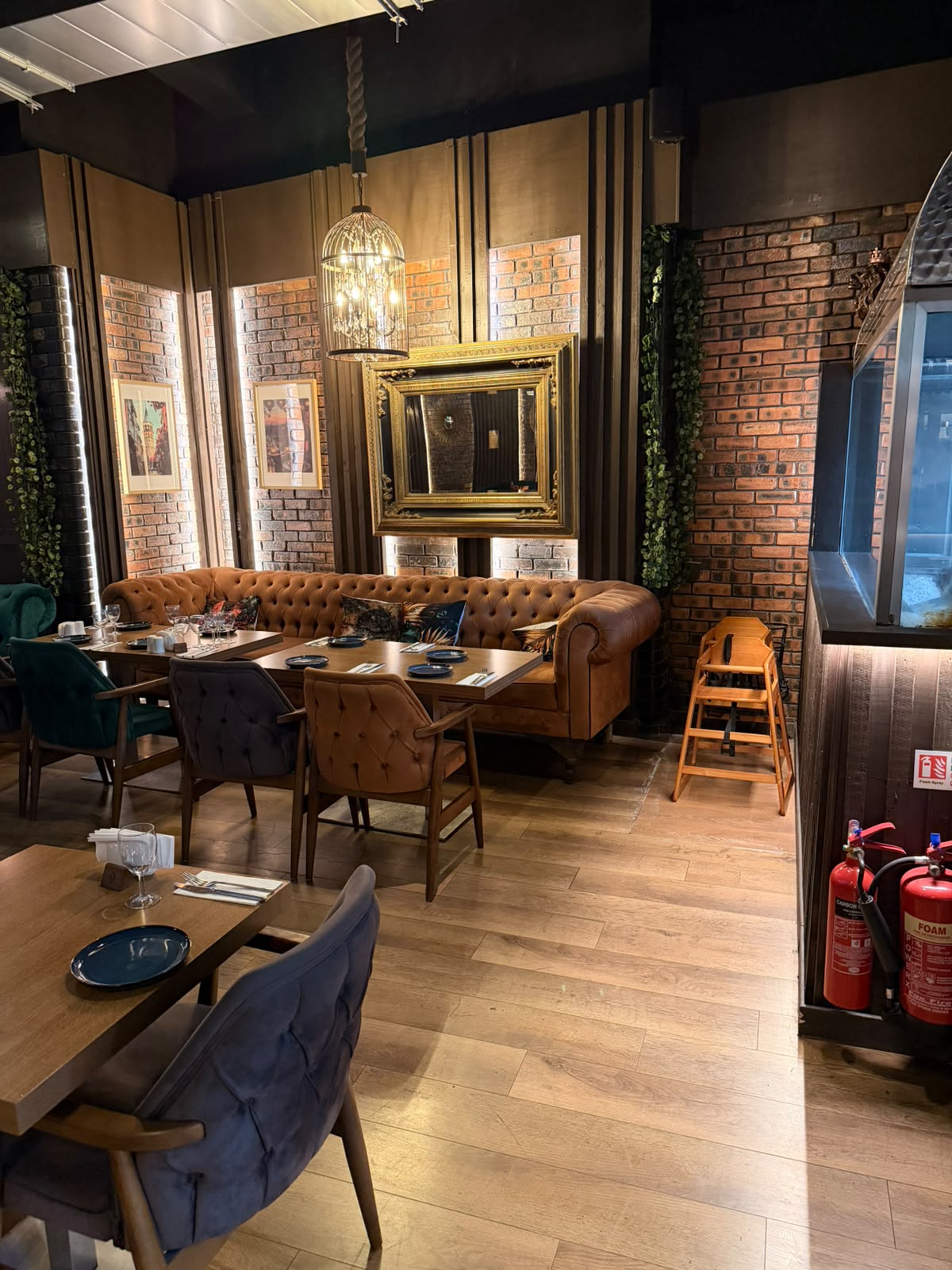 A cosy corner of The Kervan with a tan leather Chesterfield sofa, gilded mirror and birdcage chandelier.