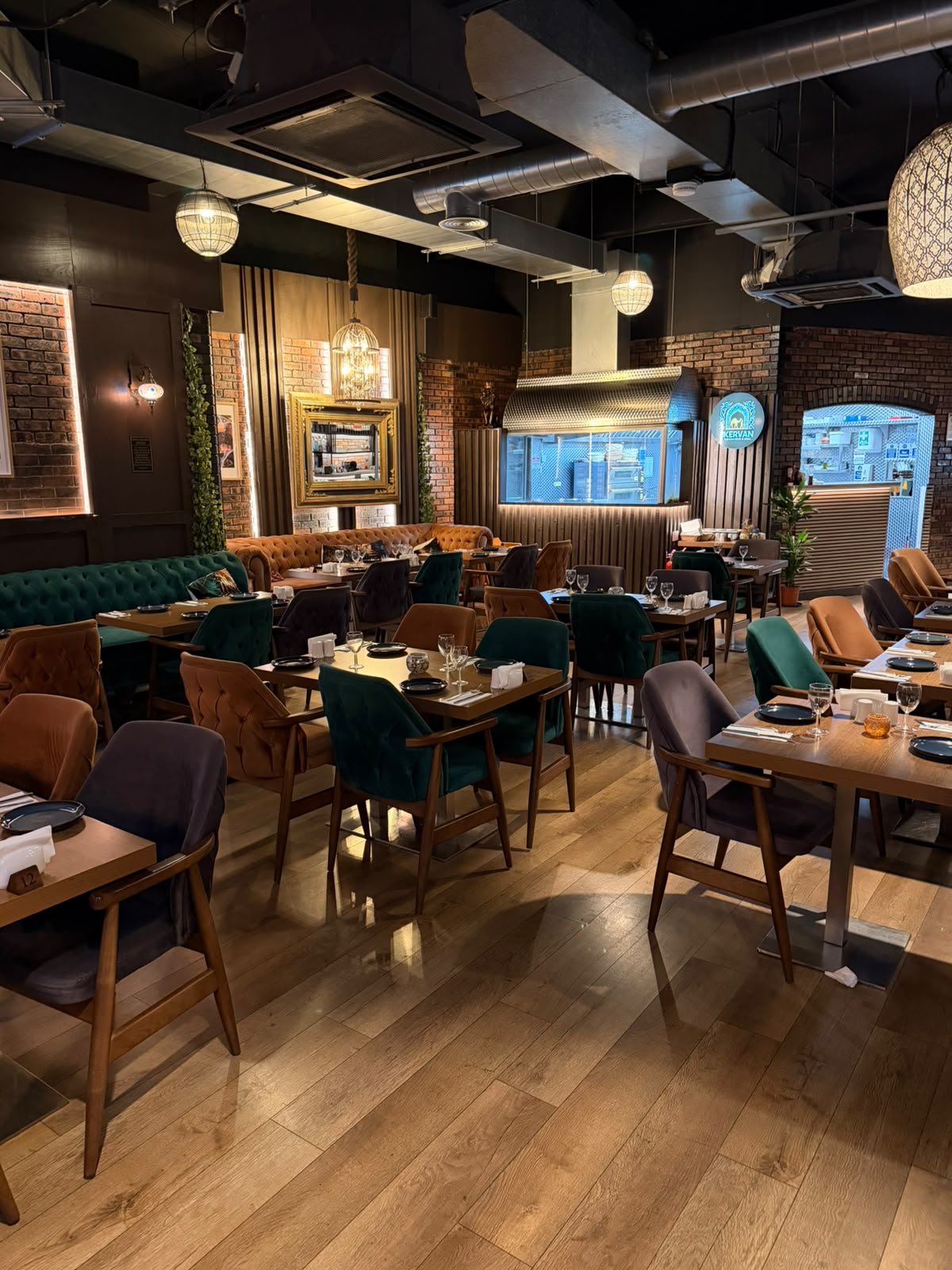 The Kervan main dining room with the open grill kitchen, pendant lights and plush armchairs.